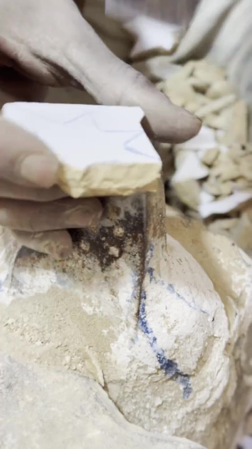 Un artisan taille une pièce de zellige au marteau tranchant