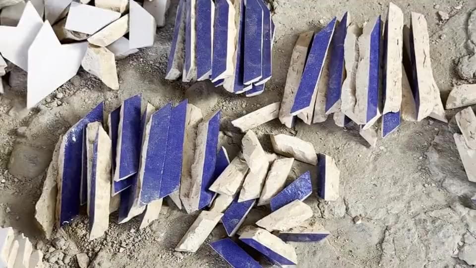 Éclats de zellige bleu et blanc triés au sol